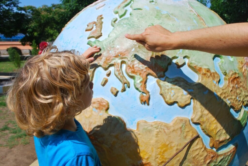 A parent teaches her child by pointing to a globe