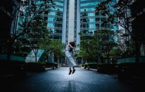 A solo female traveler jumps in the air at the Petronas Towers in Kuala Lumpar, Malaysia