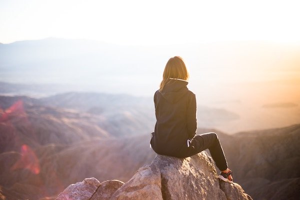 A woman sitting on a rock overlooking the sea