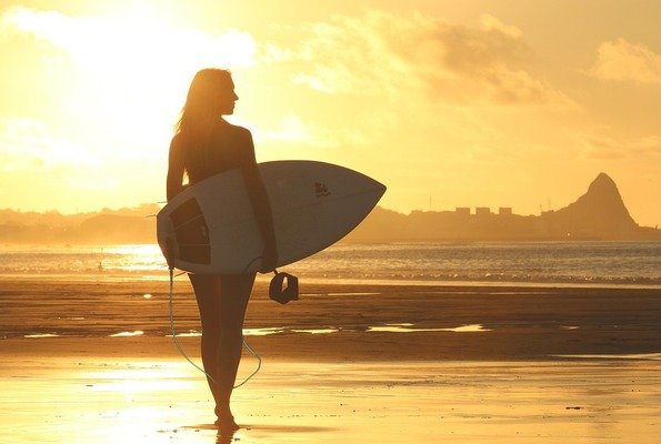 A woman at sunset with a surfboard