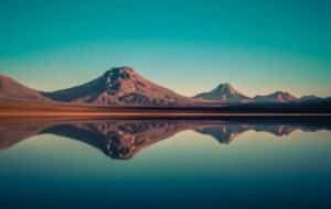 Majestic mountains reflecting in a tranquil lake under a clear sky in Chile, capturing the stunning natural beauty of the Andes.
