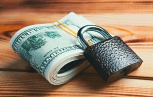 A stack of cash secured by a padlock, representing financial security and money-saving hacks.