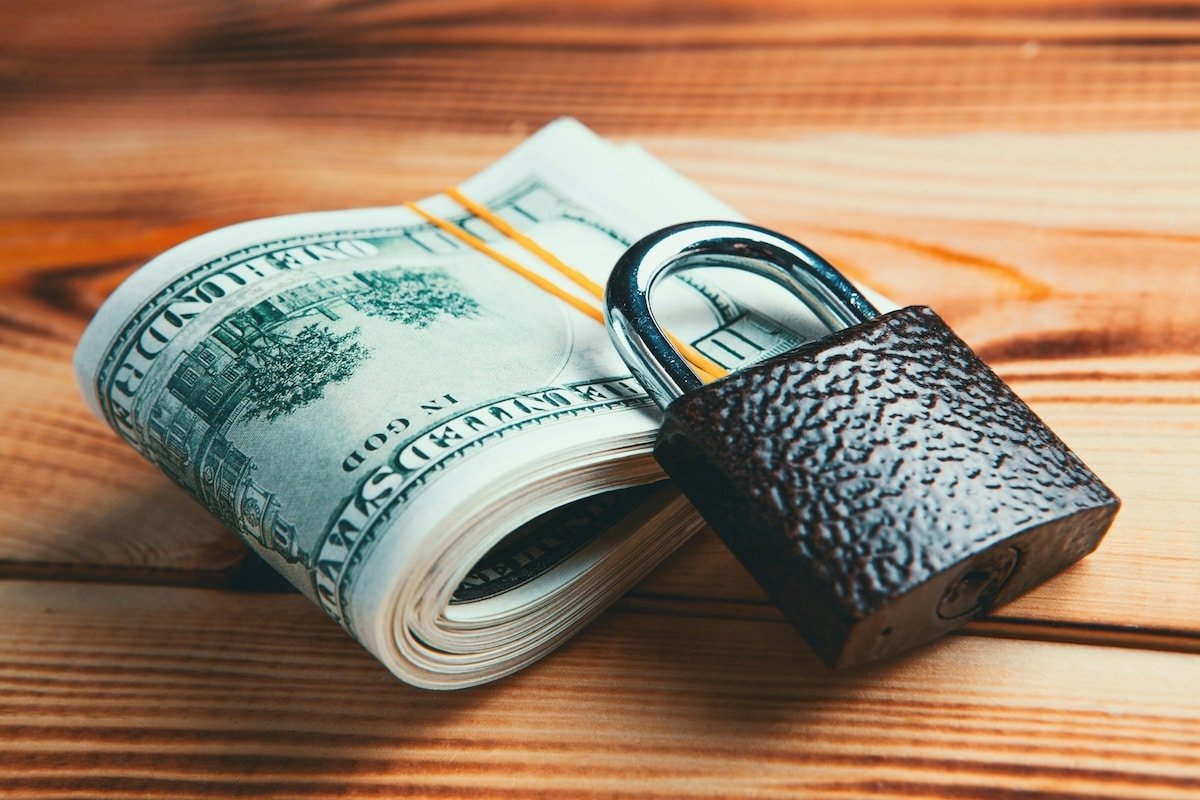 Close-up of a stack of cash secured with a padlock, symbolizing financial security and money-saving strategies