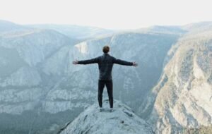 Man looking out over the snow from the top of a cliff