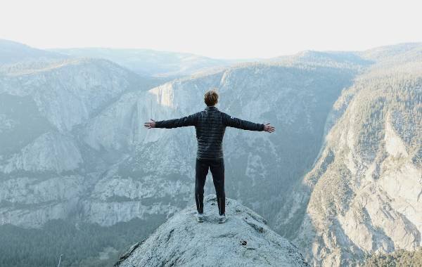 Man looking out over the snow from the top of a cliff