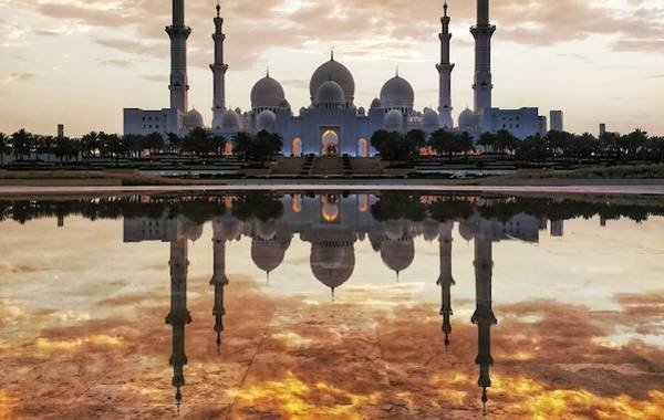 A mosque with a sun setting behind it 