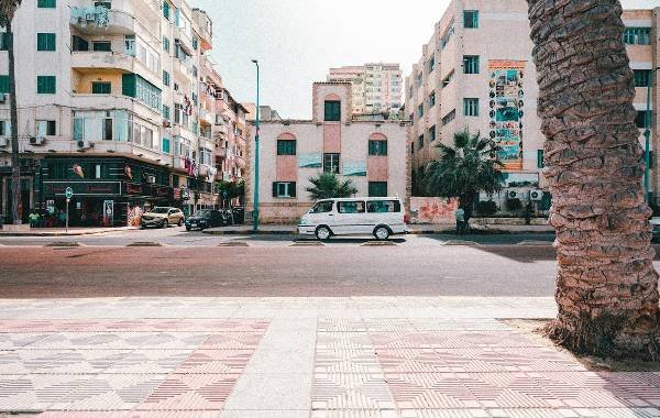 Street view of modern buildings in Alexandria, Egypt with a white van parked by the sidewalk.
