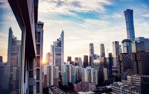 Cityscape of Beijing, China at sunset, showcasing a skyline filled with modern skyscrapers and residential buildings. The image captures the vibrant urban atmosphere and contemporary architecture of the city.