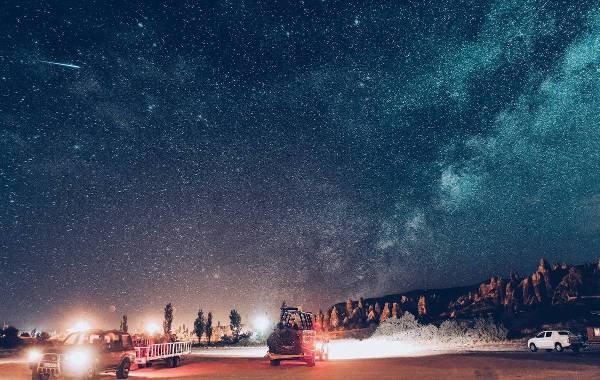 Night sky in Cappadocia, Turkey with starry landscape and vehicles in foreground