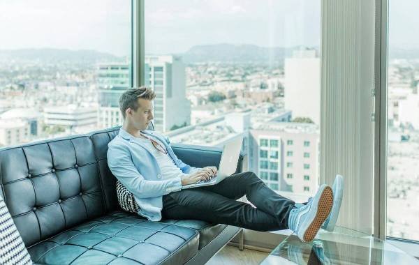 Young professional working remotely on a laptop in modern high-rise with city view