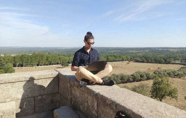 Digital nomad working on a laptop outdoors with scenic view in the background