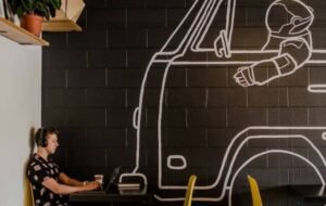 Digital nomad working on laptop in trendy cafe with space-themed wall art
