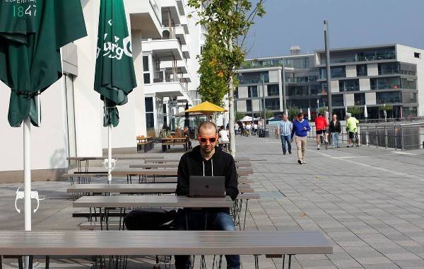 Digital nomad working on a laptop at an outdoor café by the waterfront