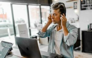 Man working on laptop with headphones in a modern café, digital nomad lifestyle featured.