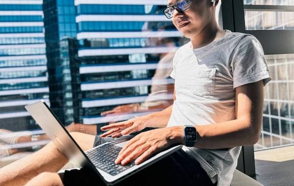 Young man working remotely on a laptop in a modern city building with large windows