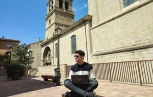 Digital nomad working on a laptop outside a historic church on a sunny day