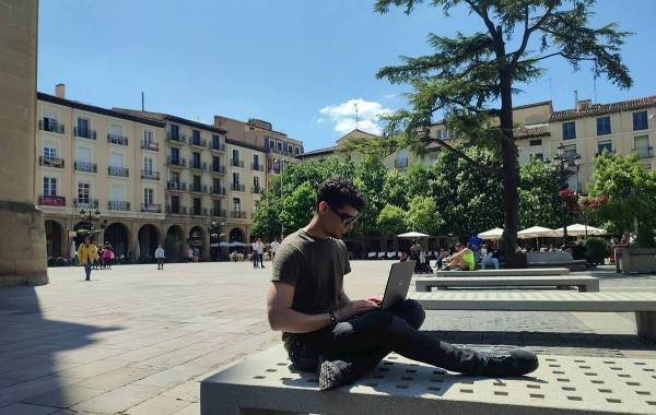 Remote worker in city plaza using laptop under the open sky