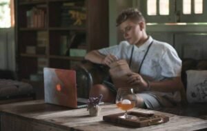 Young digital nomad working remotely with laptop on a wooden table in a cozy room