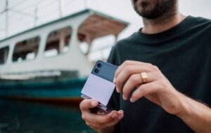 Man holding a foldable smartphone near a boat, representing digital nomad lifestyle