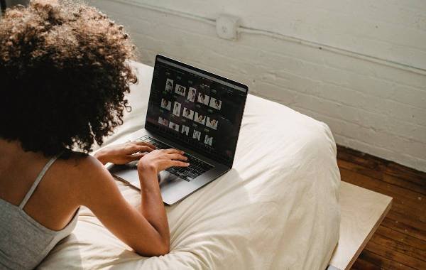 Woman working on a laptop from bed, representing digital nomad lifestyle