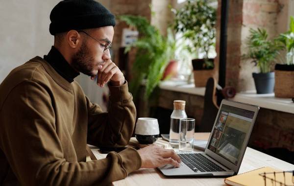 Man working on laptop in a cozy workspace with plants, representing digital nomad lifestyle.