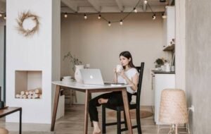 Woman working remotely in stylish home office with laptop and coffee