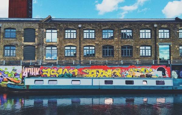 Graffiti on walls of London with a boat and river along side it  