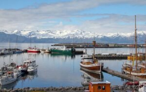 fishing boats on icy waters with snowcapped mountains in the background