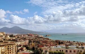 Aerial view of Naples, Italy with Mount Vesuvius and the Bay of Naples in the background under a partly cloudy sky