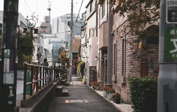 A street in Tokyo, cobblestones and electricity wires hanging. The skyscrapers in the far distance