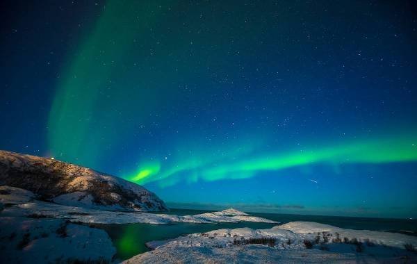 Green and blue northern lights shining over the snow