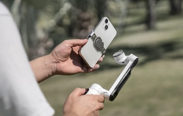 Hands holding a smartphone gimbal stabilizer in an outdoor setting