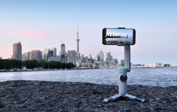 Smartphone mounted on Insta360 Flow Pro stabilizer capturing city skyline.