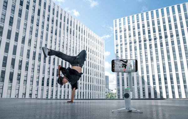 Person performing breakdance move in urban setting while being recorded by Insta360 Flow Pro stabilizer.