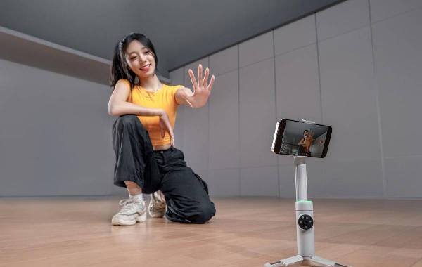 Woman demonstrating Insta360 Flow Pro camera gimbal with smartphone indoors.