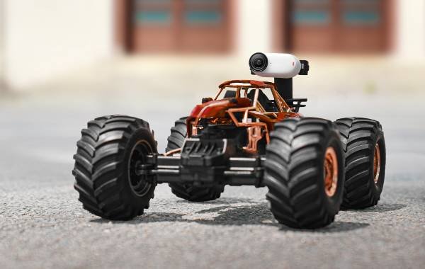 RC car with Insta360 GO 3 action camera mounted on top, showcasing large wheels and rugged design on pavement