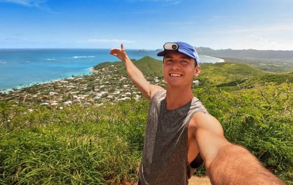 Person taking a selfie with Insta360 GO 3 camera overlooking a scenic coastal view