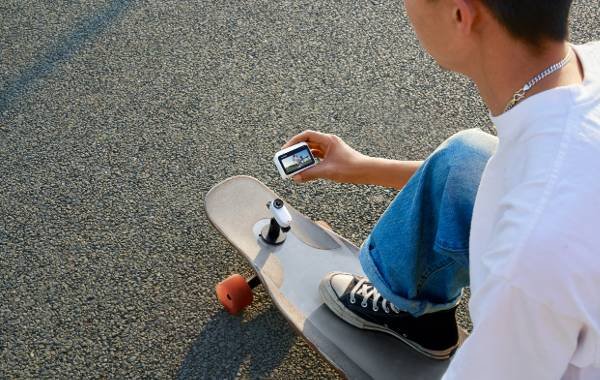 Man holding Insta360 GO 3 camera while sitting on skateboard