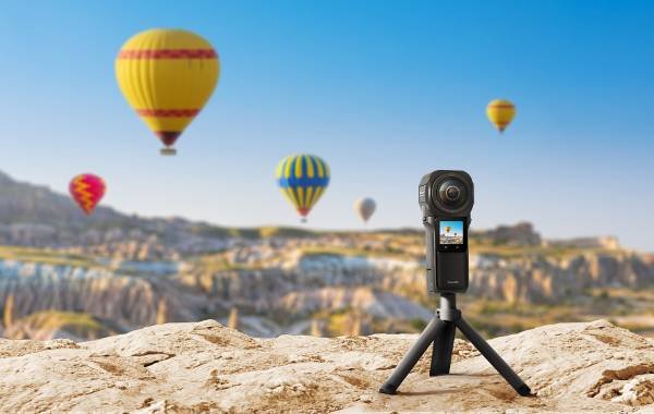 360-degree camera on a tripod capturing hot air balloons in a scenic landscape