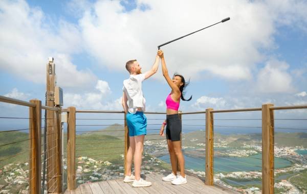 Two people using Insta360 X3 camera with selfie stick on scenic mountaintop viewpoint