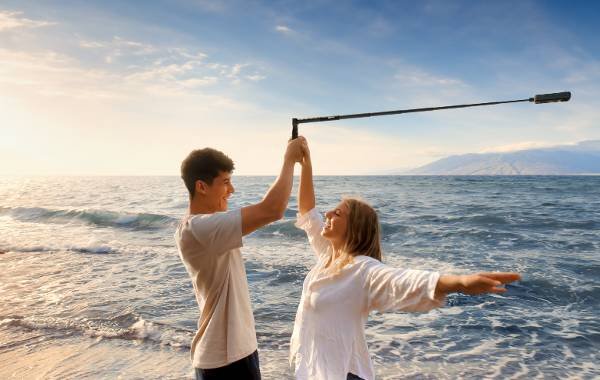 Couple capturing sunset on the beach with Insta360 camera.