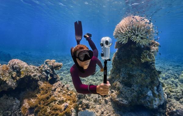 Diver using underwater camera near coral reef