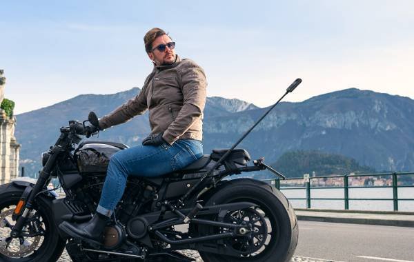 Man on a motorcycle posing with mountainous landscape in the background