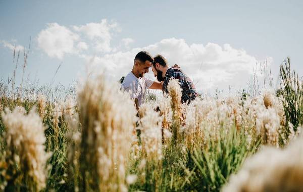 Two men showing affection in a sunny field, representing LGBT love.