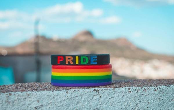 Close-up of rainbow LGBT pride bracelets against scenic outdoor background