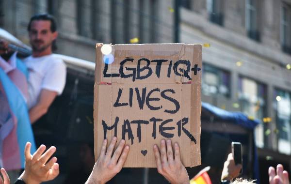 People holding a sign that reads LGBT+ Lives Matter at a pride parade.