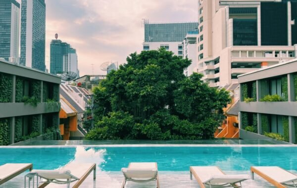 Luxury hotel in Bangkok featuring a serene infinity pool surrounded by modern architecture and lush greenery, showcasing the vibrant city skyline
