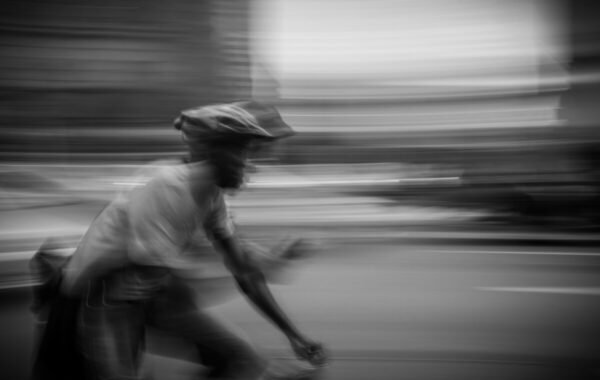 A blurred image of a delivery driver riding a bicycle, showcasing speed and movement in an urban environment