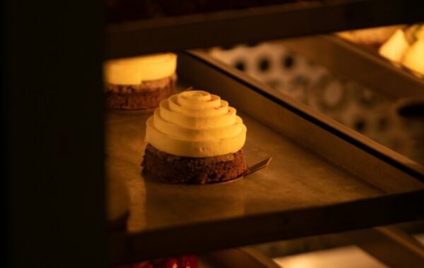 Delicious dessert featuring a creamy, swirled topping on a chocolate base, beautifully displayed in a warm, inviting bakery setting