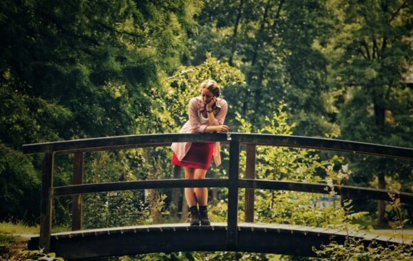 Solo traveler on a wooden bridge surrounded by lush greenery, enjoying a moment of contemplation outdoors